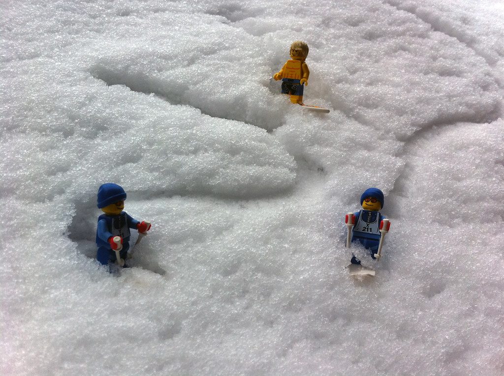 Three LEGO characters skiing