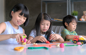 Three children playing with clay